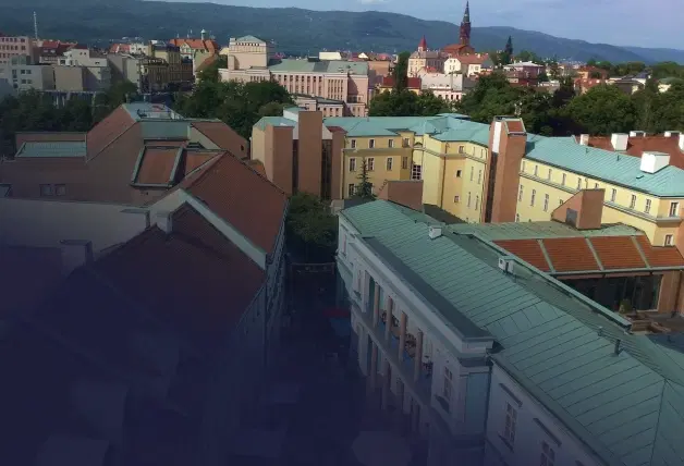 Pohled na Teplice s městskou zástavbou, věží v pozadí a horami na horizontu