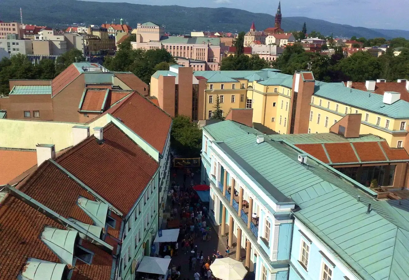 Pohled na Teplice s městskou zástavbou, věží v pozadí a horami na horizontu