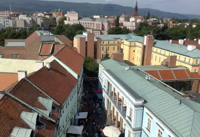 Pohled na Teplice s městskou zástavbou, věží v pozadí a horami na horizontu