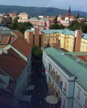 Pohled na Teplice s městskou zástavbou, věží v pozadí a horami na horizontu