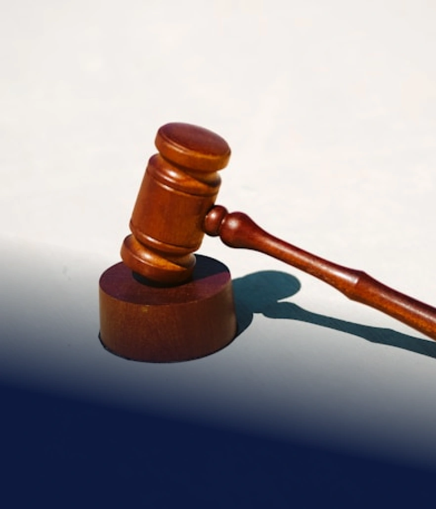 Dřevěné soudcovské kladívko leží na podstavci na světlém pozadí