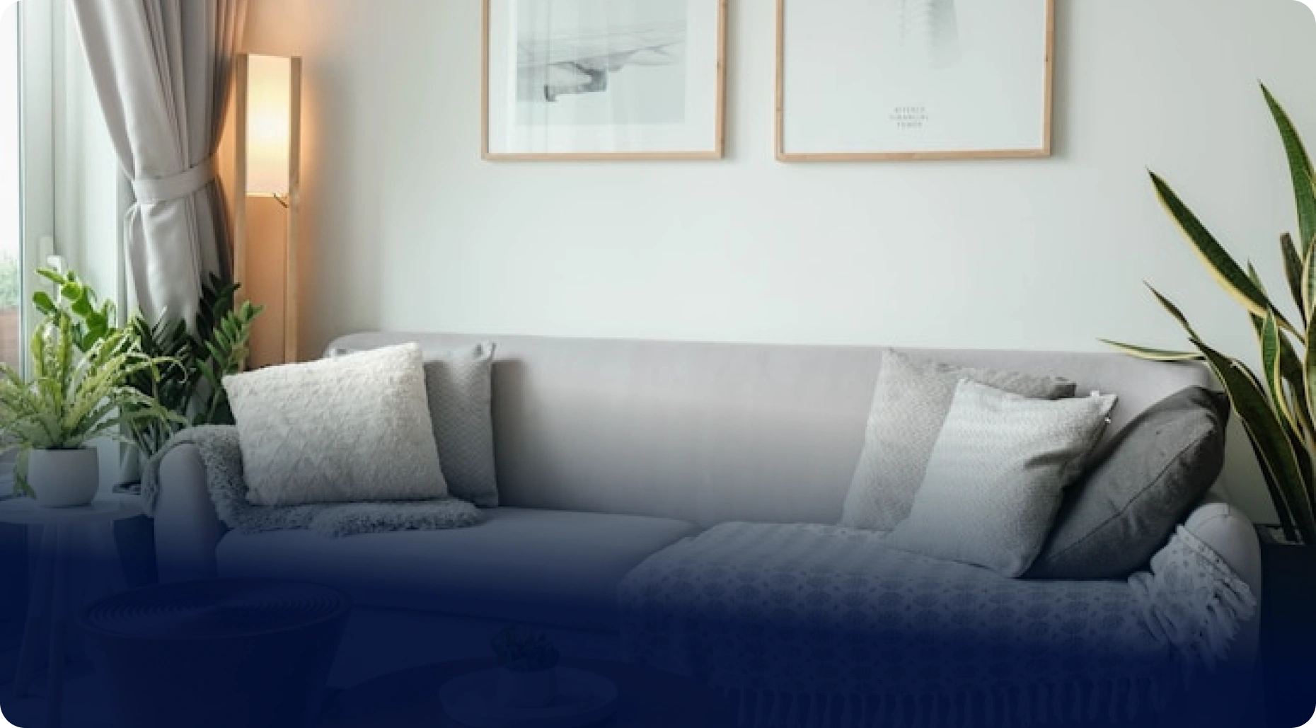 Záběr moderního obývacího pokoje s pohovkou, dřevěným stolkem, rostlinami a obrazy na zdi